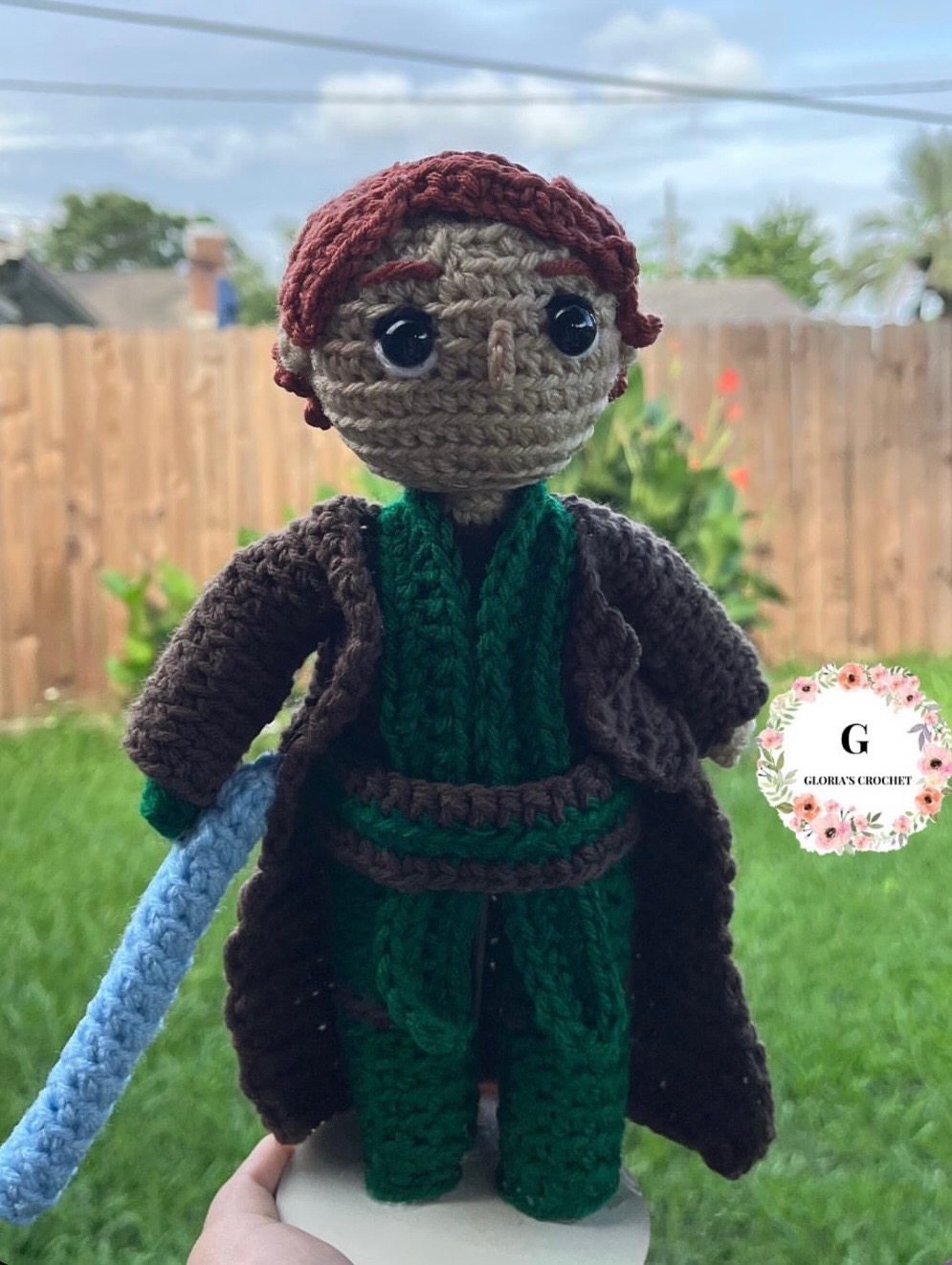Red-haired crochet wizard character plushie with green scarf and blue wand