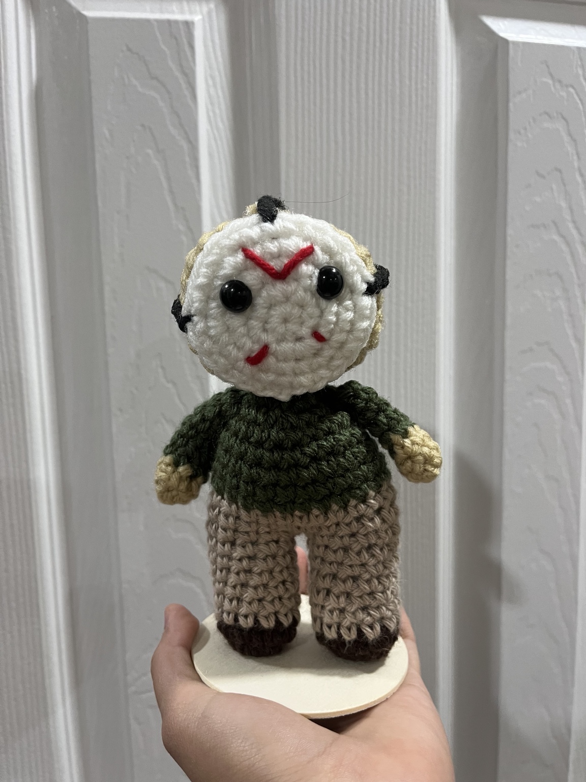 White mask crochet character plushie in a dark green sweater