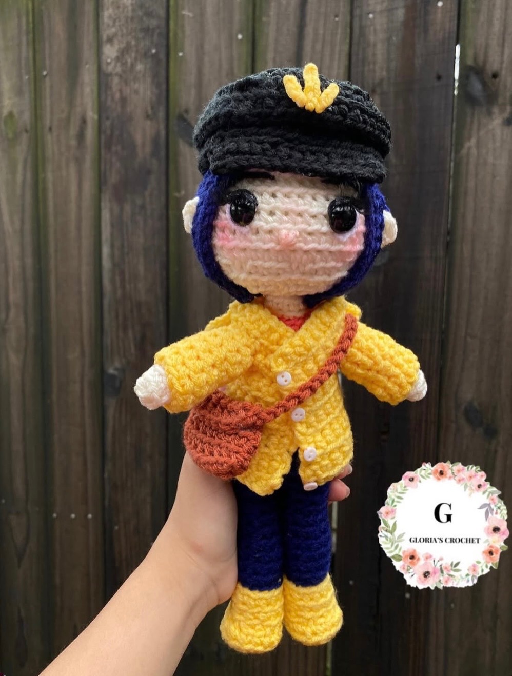 Dark blue-haired crochet character plushie in a yellow jacket